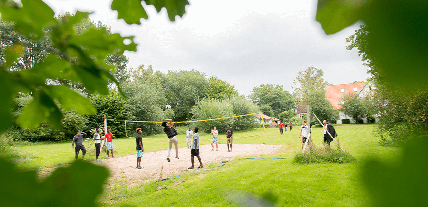 Junge Menschen spielen Volleyball im Aussenbereich des Haus Kayhauserfeld der Paritaetischen Suchthilfe Niedersachsen